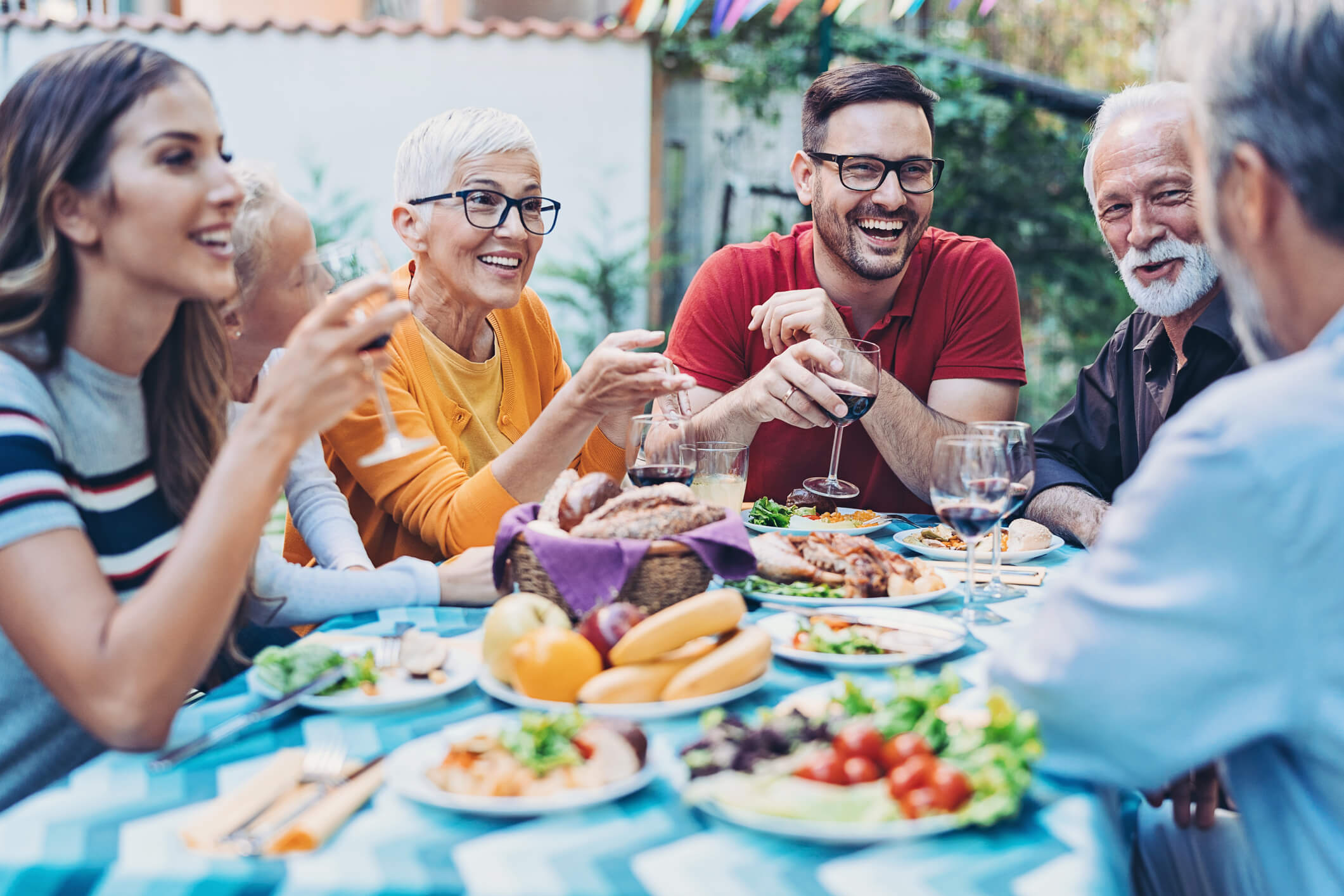 Happy family gathered together around a dinner table outside